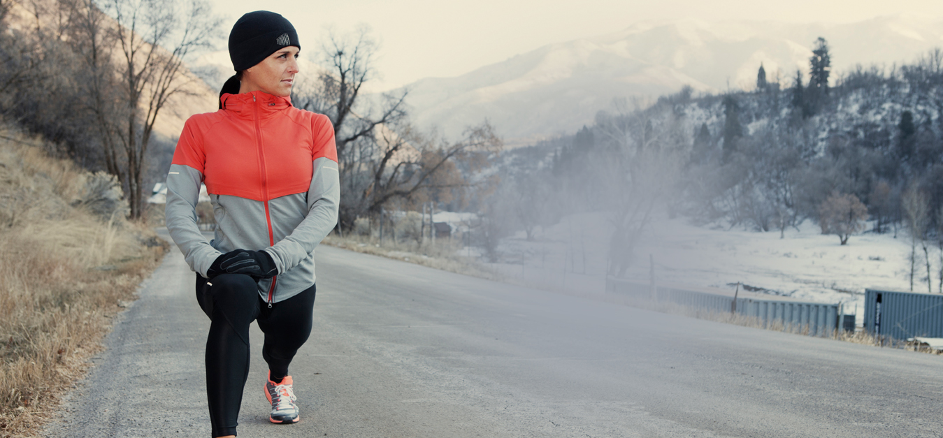 female athlete stretching out in cold with BodyWarmer Thermal Hoop inside running gear